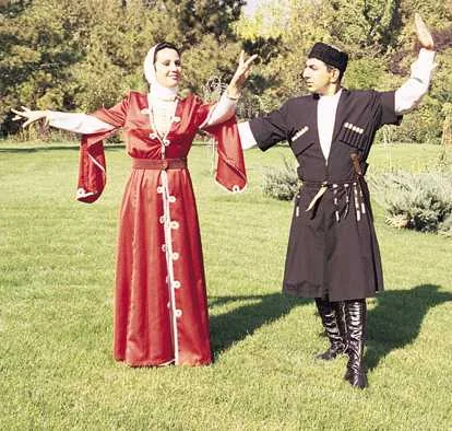 Kırmızı kadın kıyafeti ve siyah çuhalı, kalpaklı erkek kıyafetiyle halk oyunu