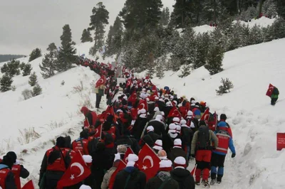 Karlı ormanda bayraklarla yürüyen kalabalık